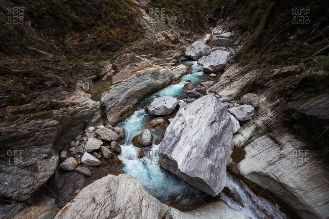 High angle of wonderful scenery of clear river flowing among huge boulders in rocky mountainous terrain in Hualien City