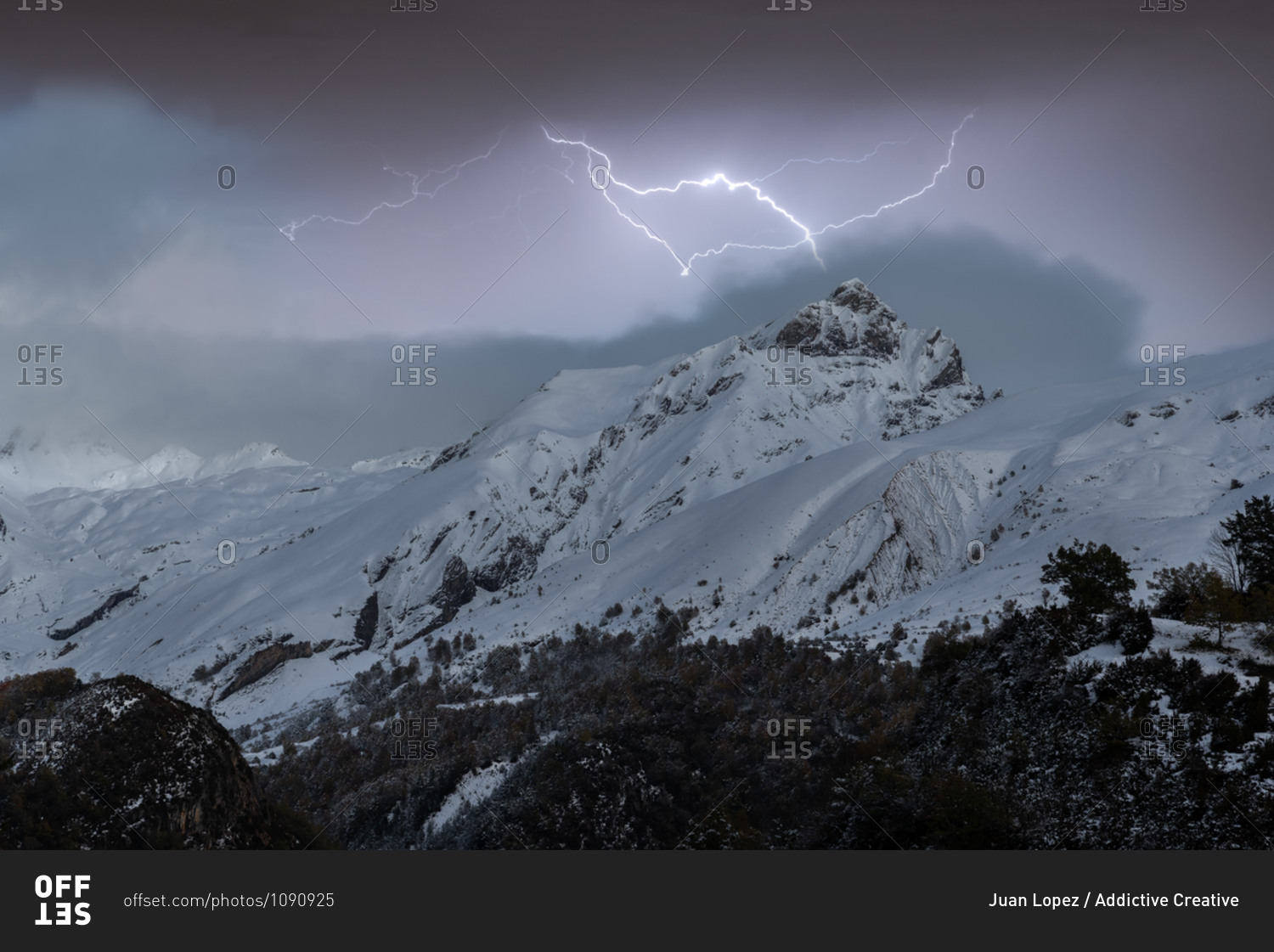 Scenery of mountain range covered with snow under thunderstorm sky with bright lightnings in winter