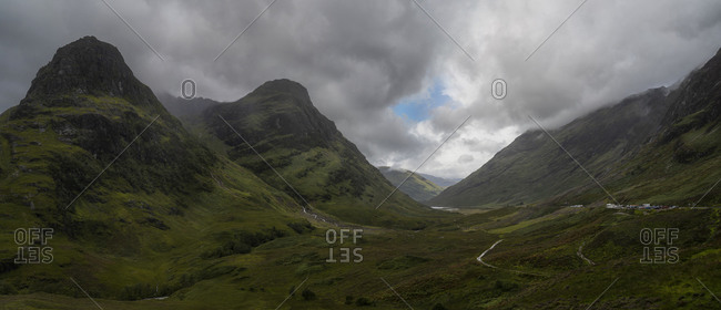 Breathtaking panorama of landscape with rocky mountains against gray cloudy sky in Scotland
