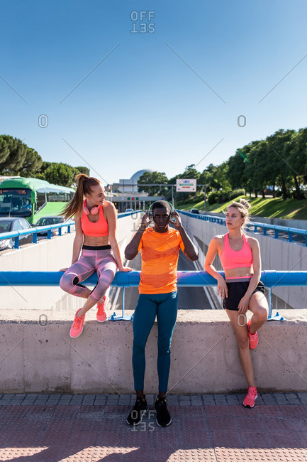 Group of multiracial runners in sportswear standing on street on sunny day during training