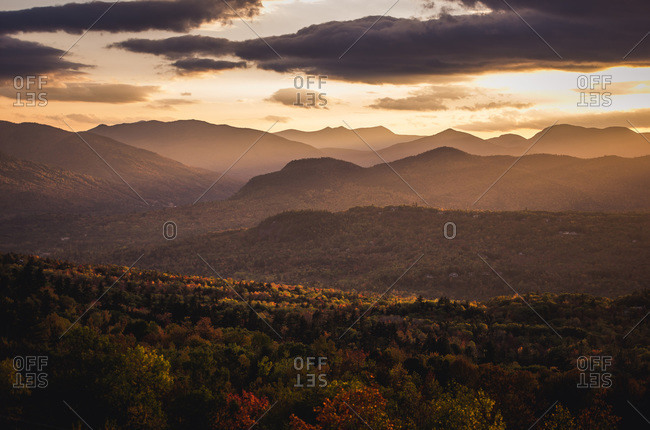 A dramatic sunset casts light over foliage in northern new hampshire