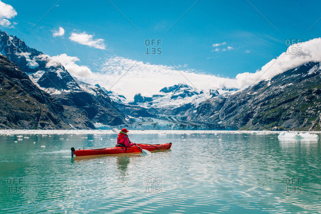 Woman kayaking in glacier bay national park with glacier in background
