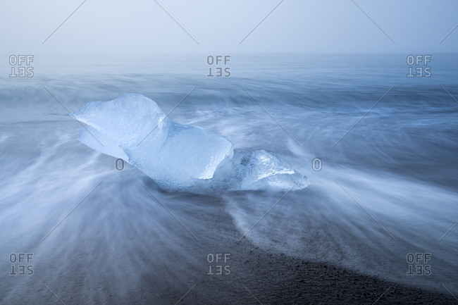 Chunk of ice on sea shore at diamond beach near jokulsarlon glacier lagoon in foggy weather, iceland