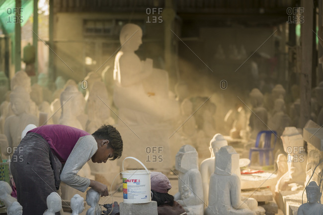 Mandalay, mandalay region, myanmar (burma) - january 12, 2018: young marble carvers carving buddha statue, mandalay, myanmar