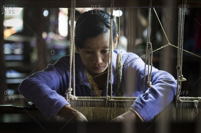 Nyaungshwe, shan, myanmar (burma) - january 20, 2018: burmese woman weaving on loom, lake inle, myanmar