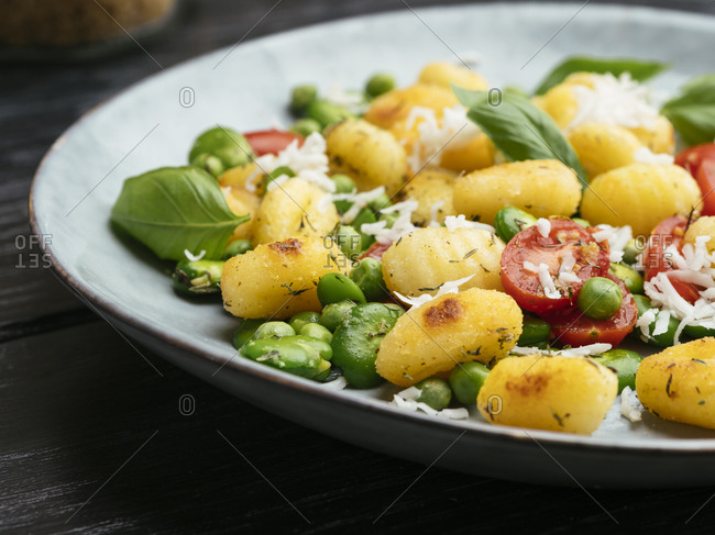 Fried gnocchi with fava beans, peas, tomatoes and vegan cheese