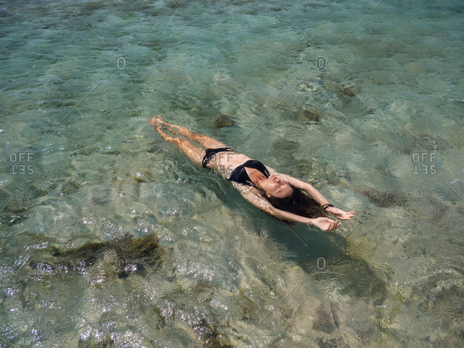 Young brunette woman relaxing in the sea with mountain backdrop