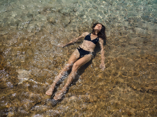 Young brunette woman relaxing in the sea with mountain backdrop