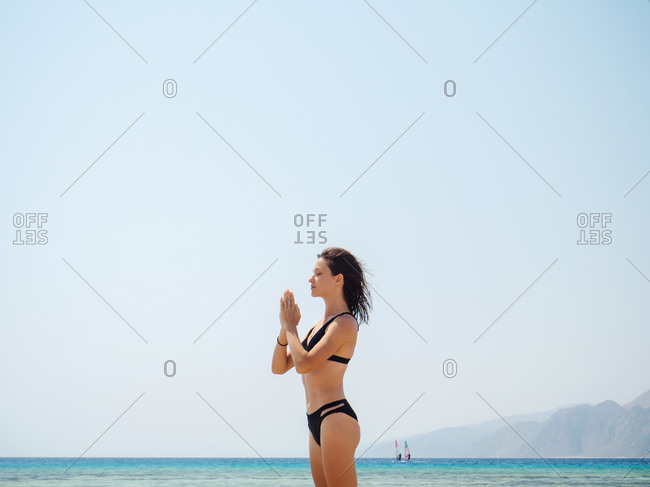 Young brunette woman doing yoga on the beach near sea
