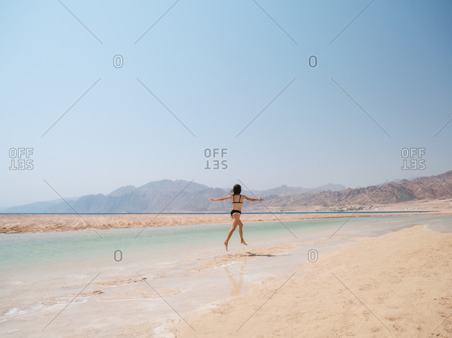 Young brunette woman relaxing on the beach near sea and mountains