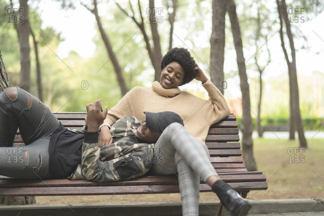 African couple in love lying on the park bench