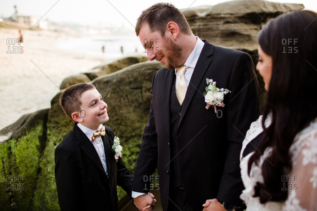 Newlyweds posing with nine year old son on beach in san diego