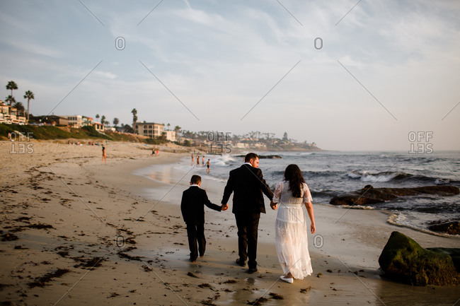 Newlyweds & nine year old son walking along beach in san diego