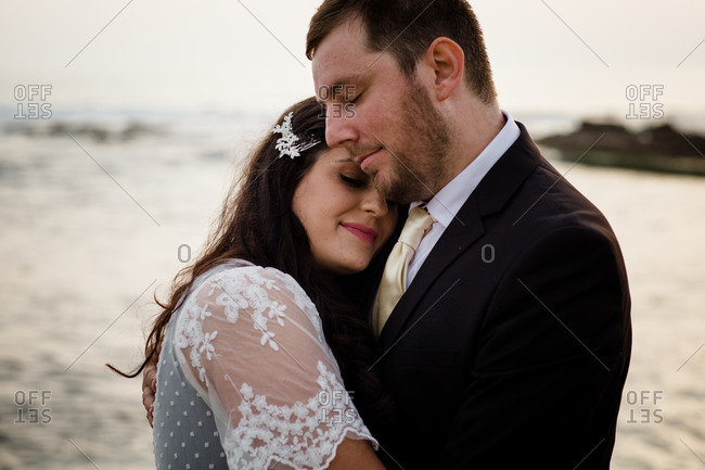Newlyweds posing on beach at sunset in san diego
