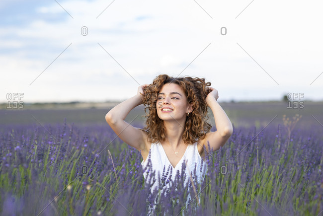 Woman with curly hair wearing a hat in a lavender field