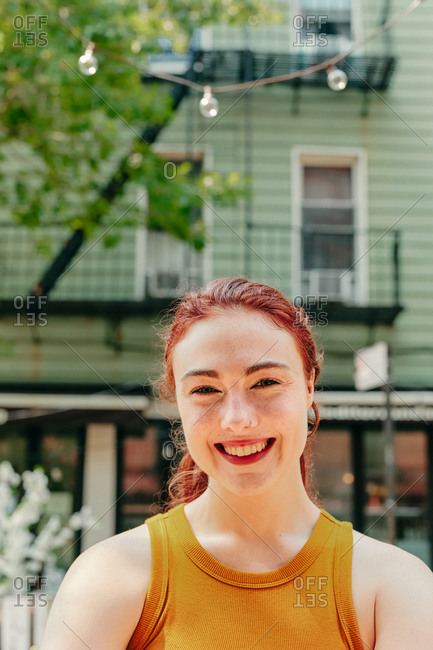 Portrait of a young woman sitting in an outdoor patio.