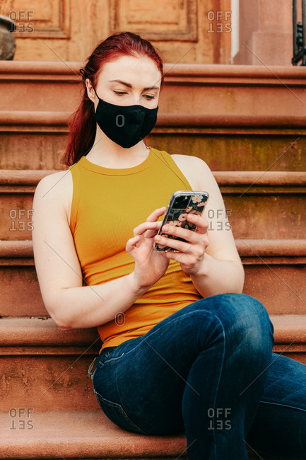 Portrait of a young woman sitting on brooklyn stoop talking on phone.
