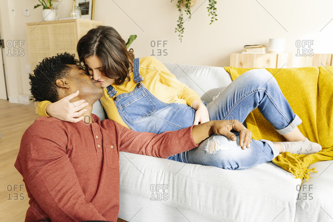 Husband kissing his pregnant wife on a sofa. interracial couple concept