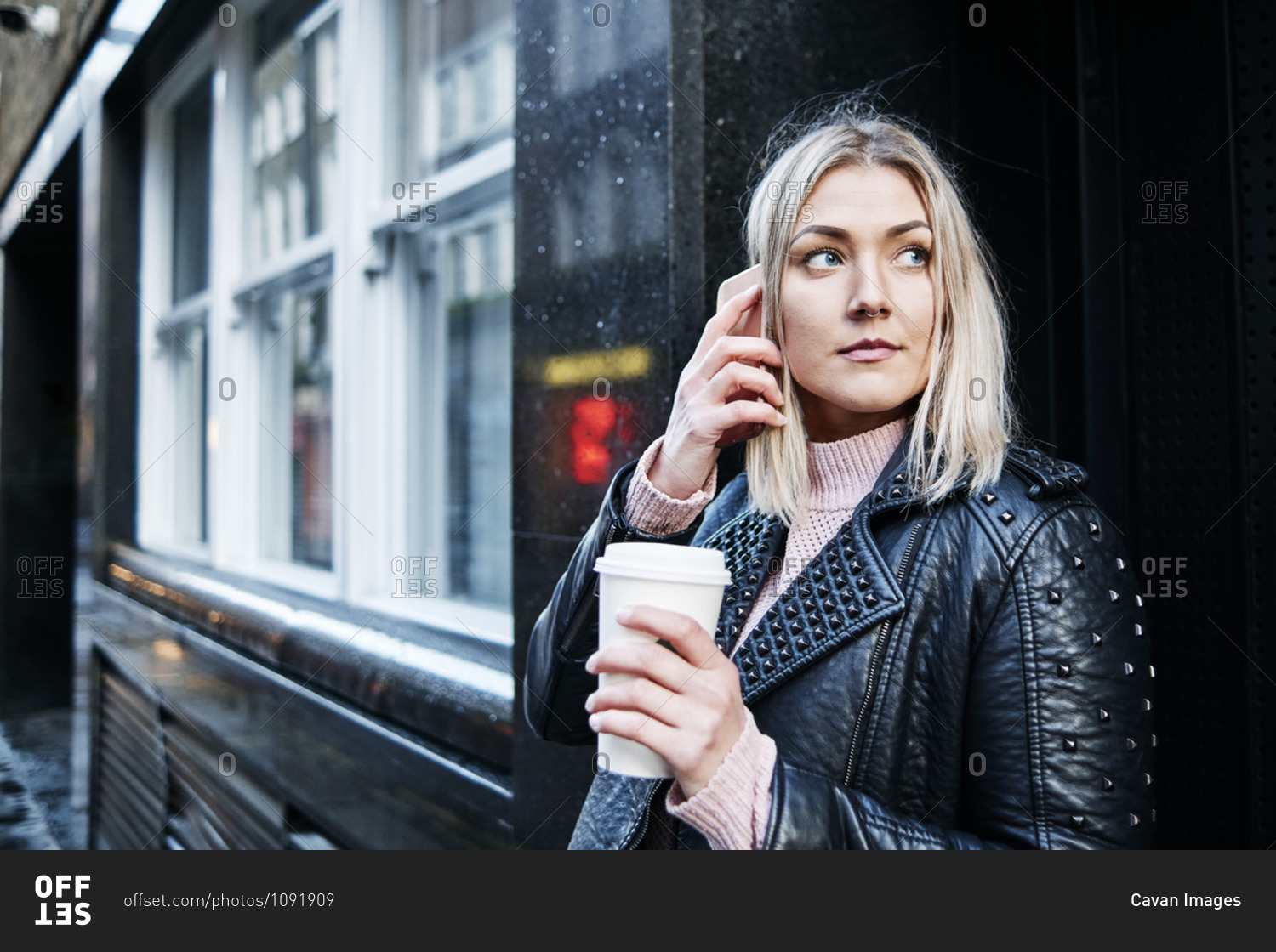 Pretty blonde woman stand on the street giving a phone call and drink coffee. businesswoman holding cup of coffee. winter.