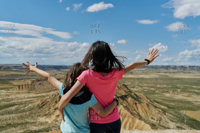 Little sisters in viewpoint observing with open arms a desert mountain in the bardenas reales national park in navarra, spain. travel concept