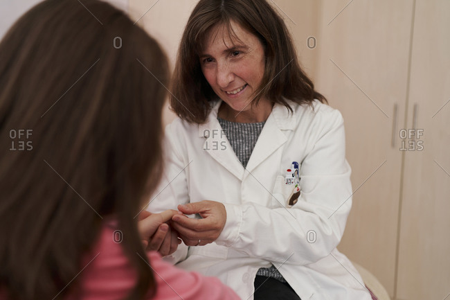 Close-up of a doctor treating a girl's finger in her room with a