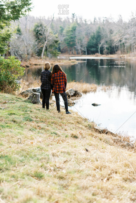 A couple standing by the shore of a river together holding hands