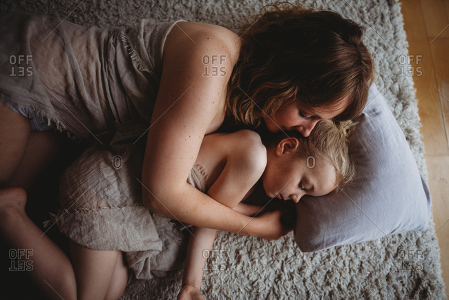 Mother and daughter hugging sleeping on the ground in bedroom