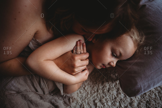 Close up of hands together of mother kissing her daughter in bed
