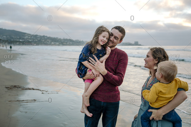 Mom & dad holding daughter and son enjoy off-season sunset at beach