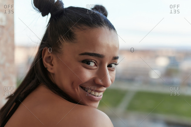 Smiling young ethic woman standing on balcony looking at camera