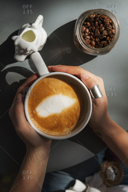 cup of cappuccino in hand stock photos - OFFSET