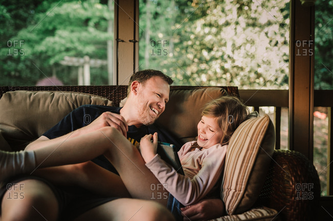 Father and daughter sitting on outdoor sofa laughing together