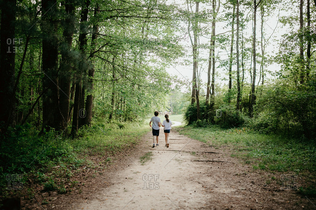 Rear view of two kids hiking in the woods