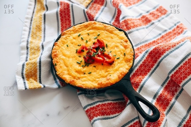 Cheesy skillet appetizer on marble surface with towel
