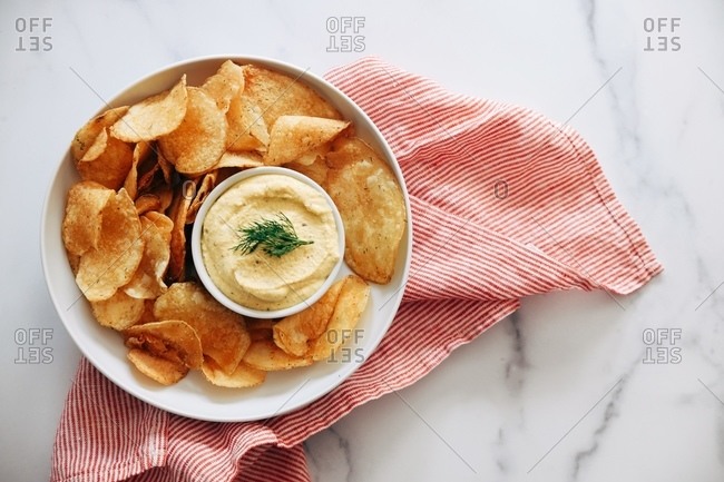 Overhead view of hummus with kettle chips on marble surface