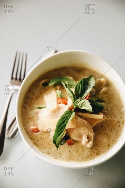 Overhead view of a bowl of delicious soup with chicken and basil