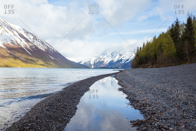 Snowy mountains in clouds, viewed from shore of kenai lake, alaska
