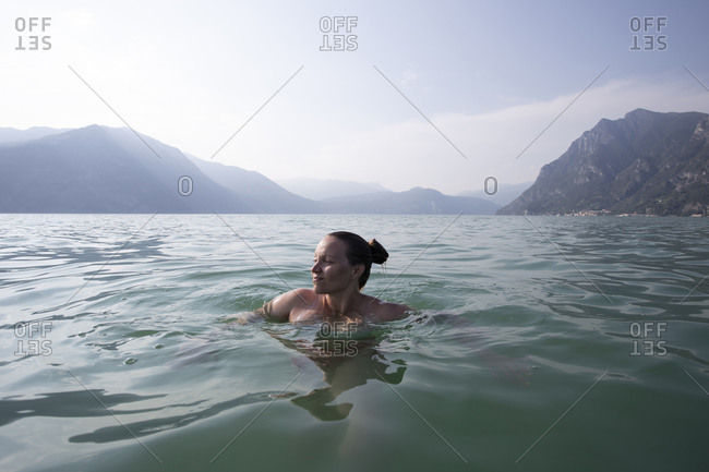 A young woman floating in the middle of a lake in italy