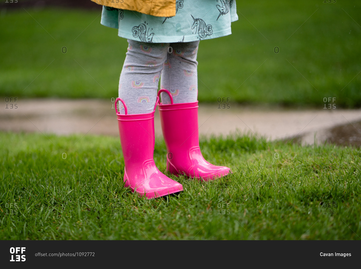 Legs view of little girl in bright pink rain boots in yard