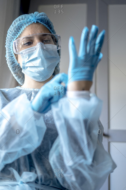 Medicine and surgery theme: doctor putting on protective blue gloves