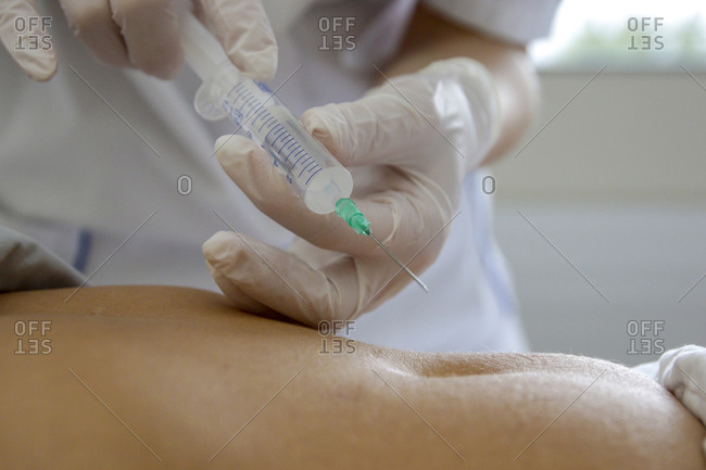 A caregiver is about to prick a patient in the abdomen