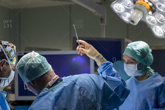 A surgeon sews up a patient in the operating room