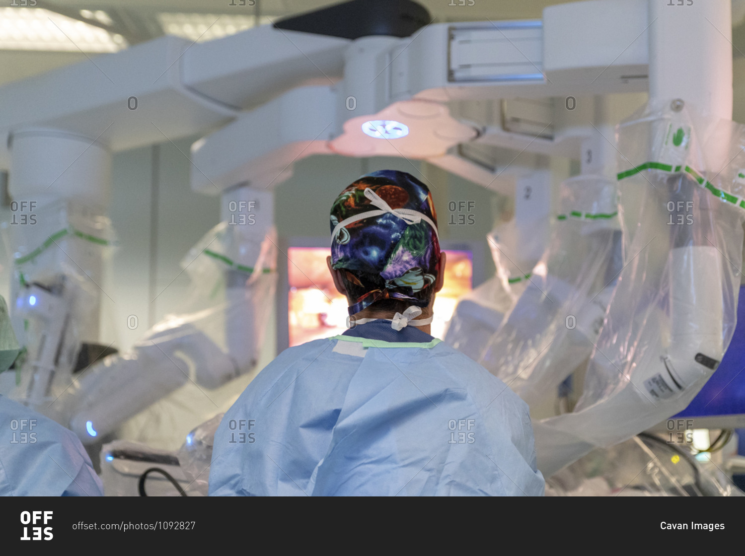 A surgeon stands in front of a robot operating a patient