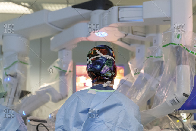 A surgeon stands in front of a robot operating a patient