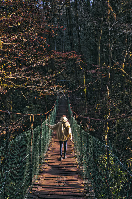 Young woman crossing  suspension bridge