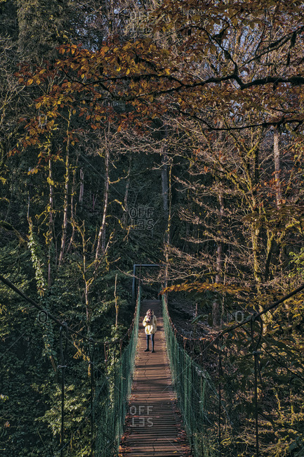 Young woman crossing  suspension bridge