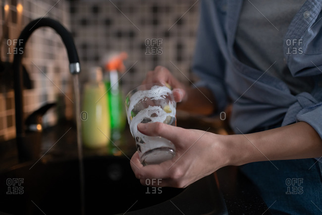 Woman washing glass with sponge and detergent