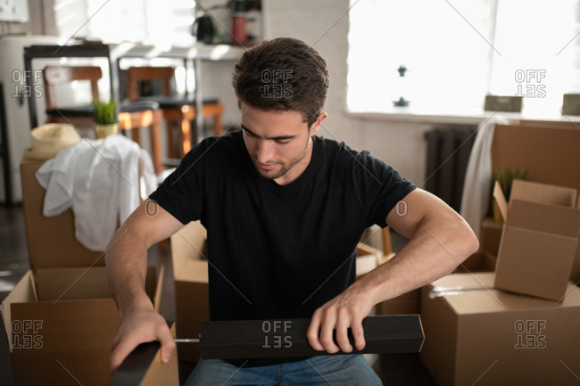 Young man assembling table in new apartment