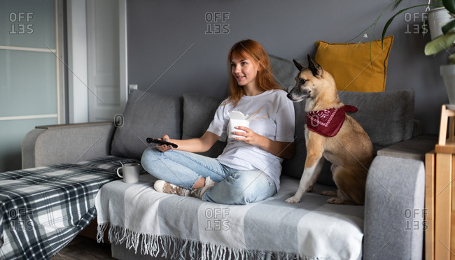 Cheerful woman watching tv with dog