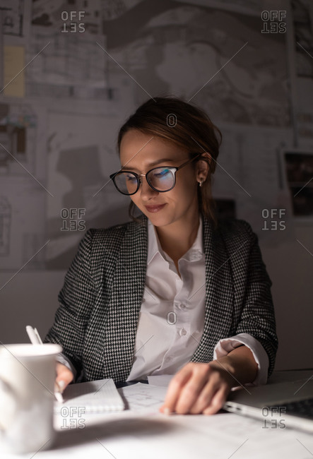Glad businesswoman making notes at night